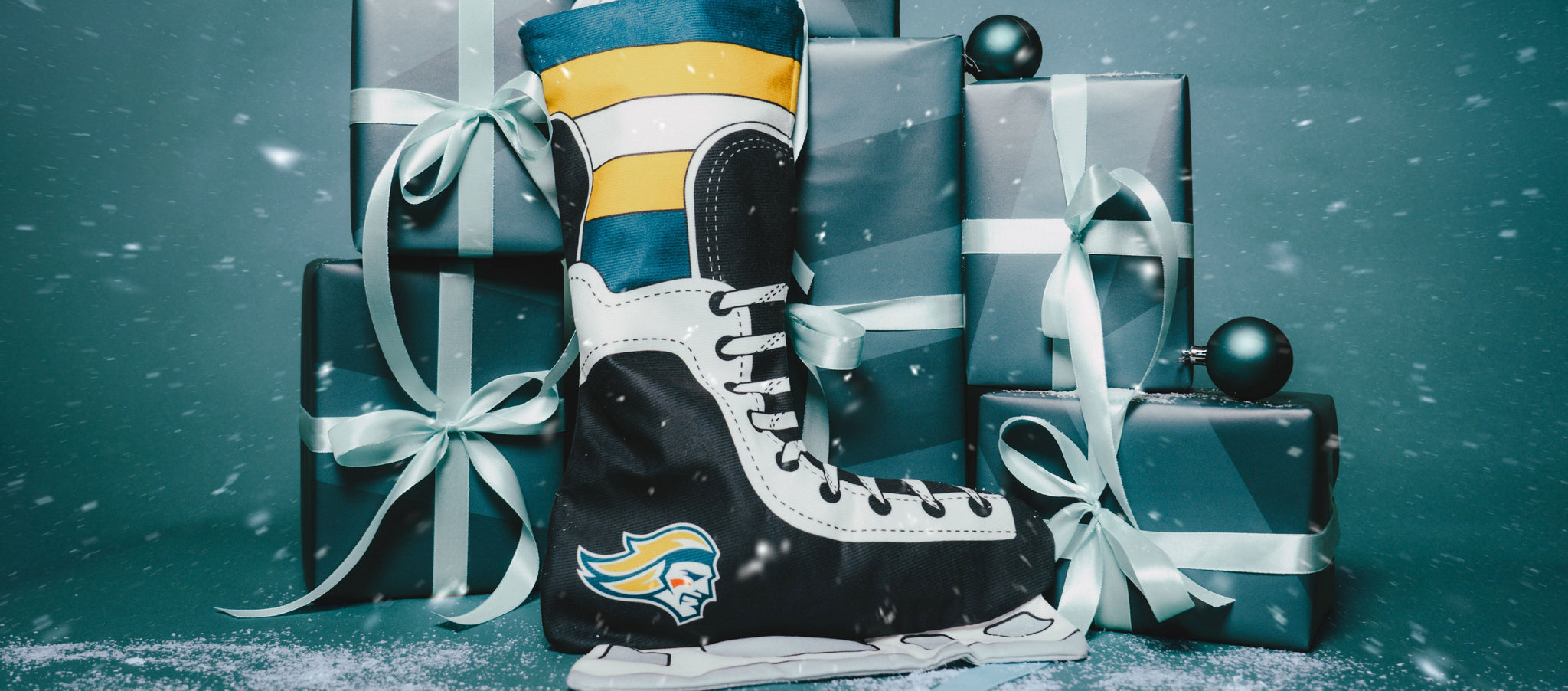 A hockey skate-shaped Christmas stocking with a sports logo is displayed in front of several blue gift boxes with white ribbons and ornaments, with snow falling.