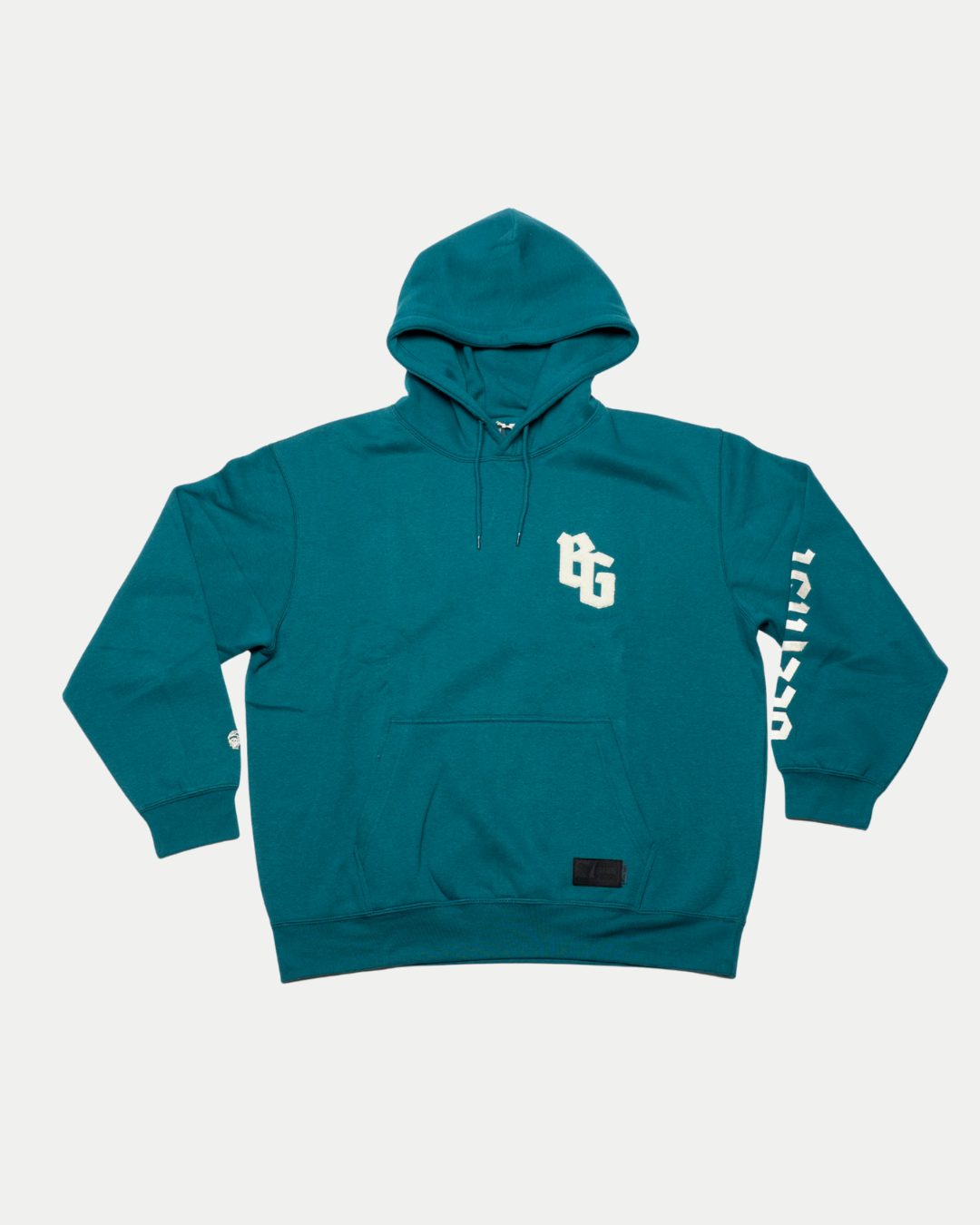 The Belfast Giants BG Hoodie Teal features a white BG chest graphic, "BELFAST" print on the right sleeve, front pocket, adjustable drawstring hood, and ribbed cuffs and hem for comfort.