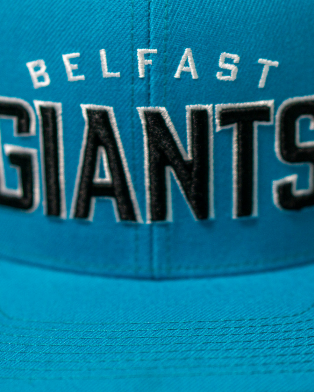 The Belfast Giants Teal Snapback Cap features bold white and black "BELFAST GIANTS" embroidery and a classic team crest, making this stylish blue cap a standout fan accessory.