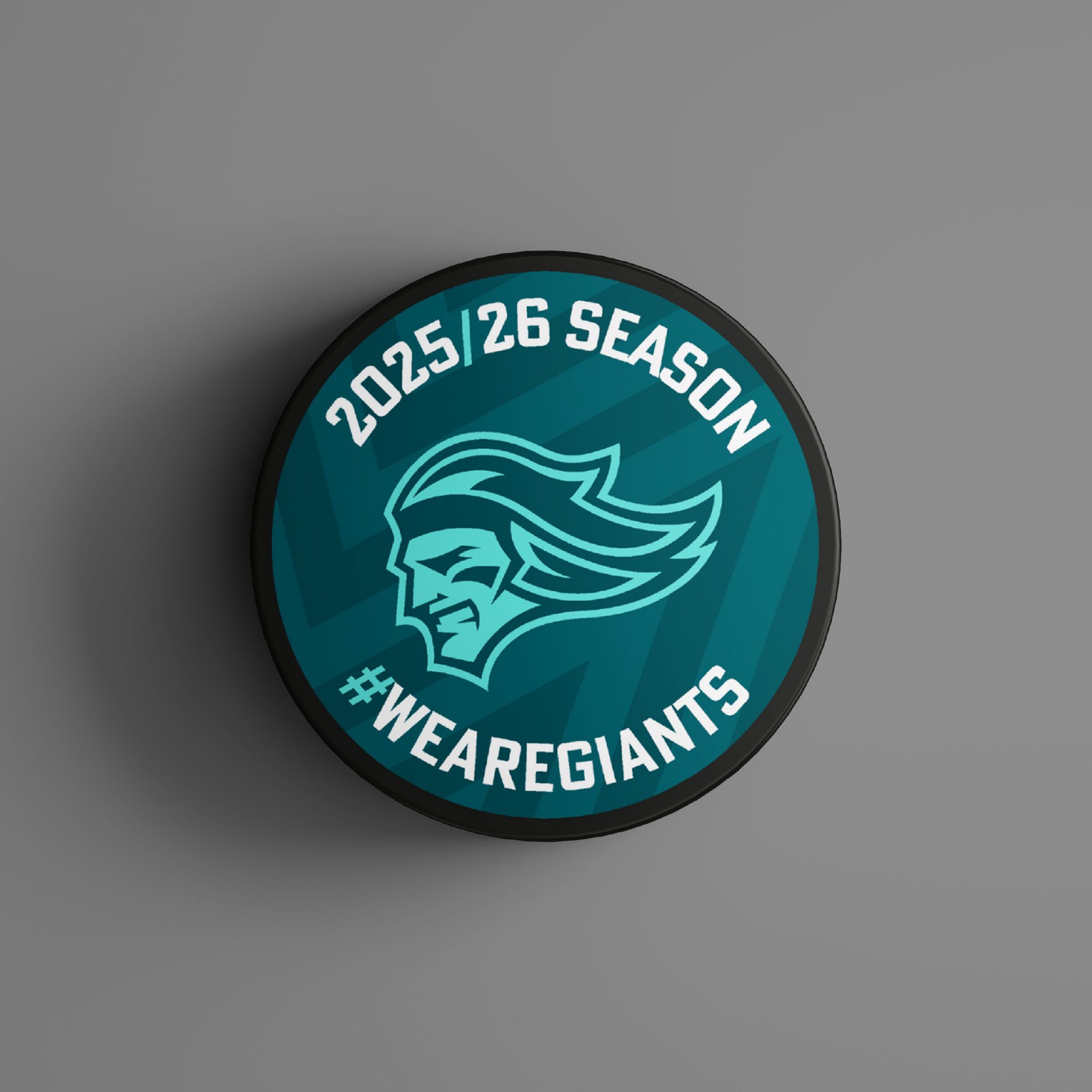 The Logo Season Puck Teal 25-26 from Belfast Giants Store by National Merchandise showcases a teal and white design with a giant head logo, 2025/26 SEASON at the top, and #WEAREGIANTS at the bottom on a teal background.