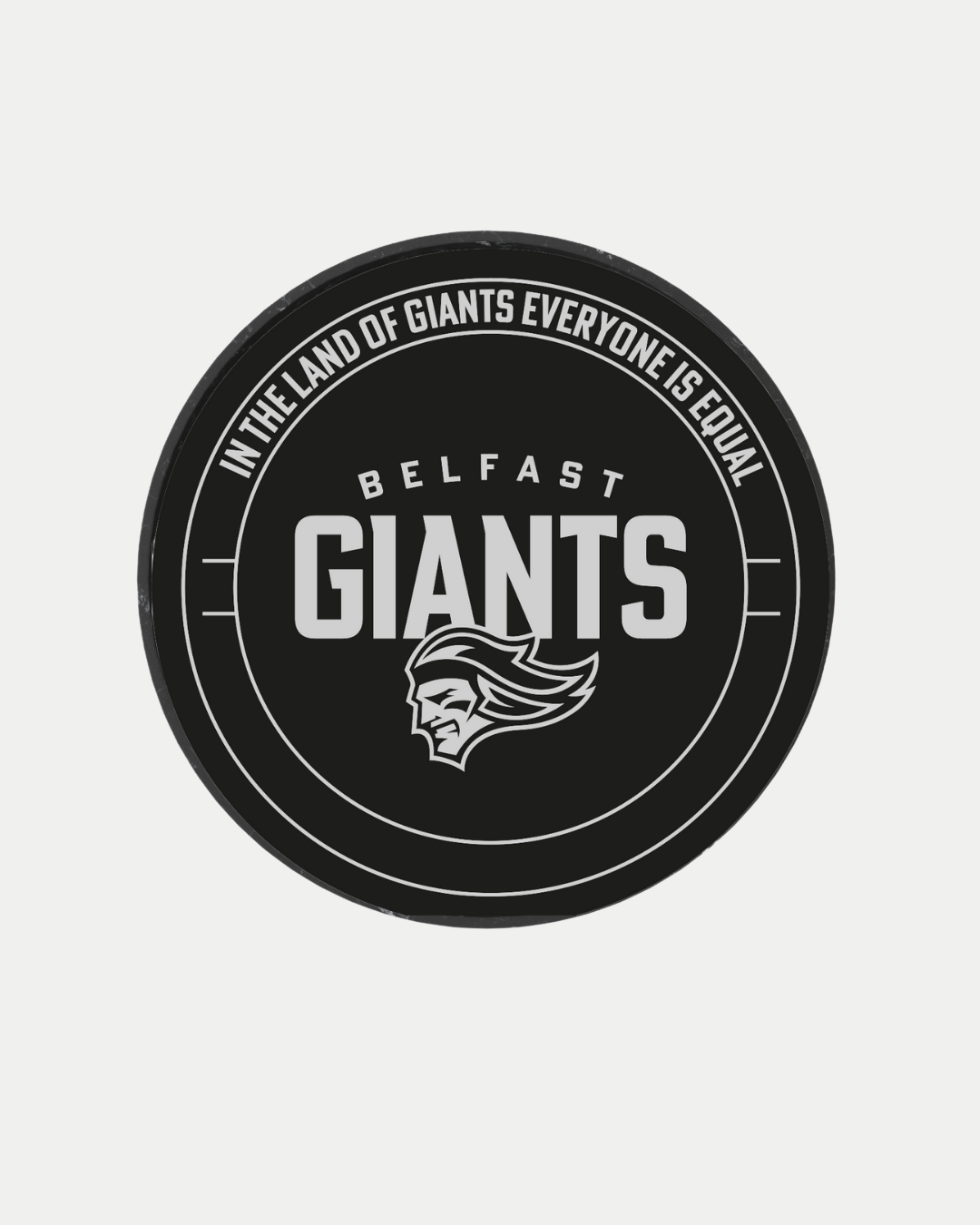 The Belfast Giants Statue Puck is a black hockey puck featuring the Belfast Giants brand and a white stylized face logo, with "In the land of giants everyone is equal" around the edge.