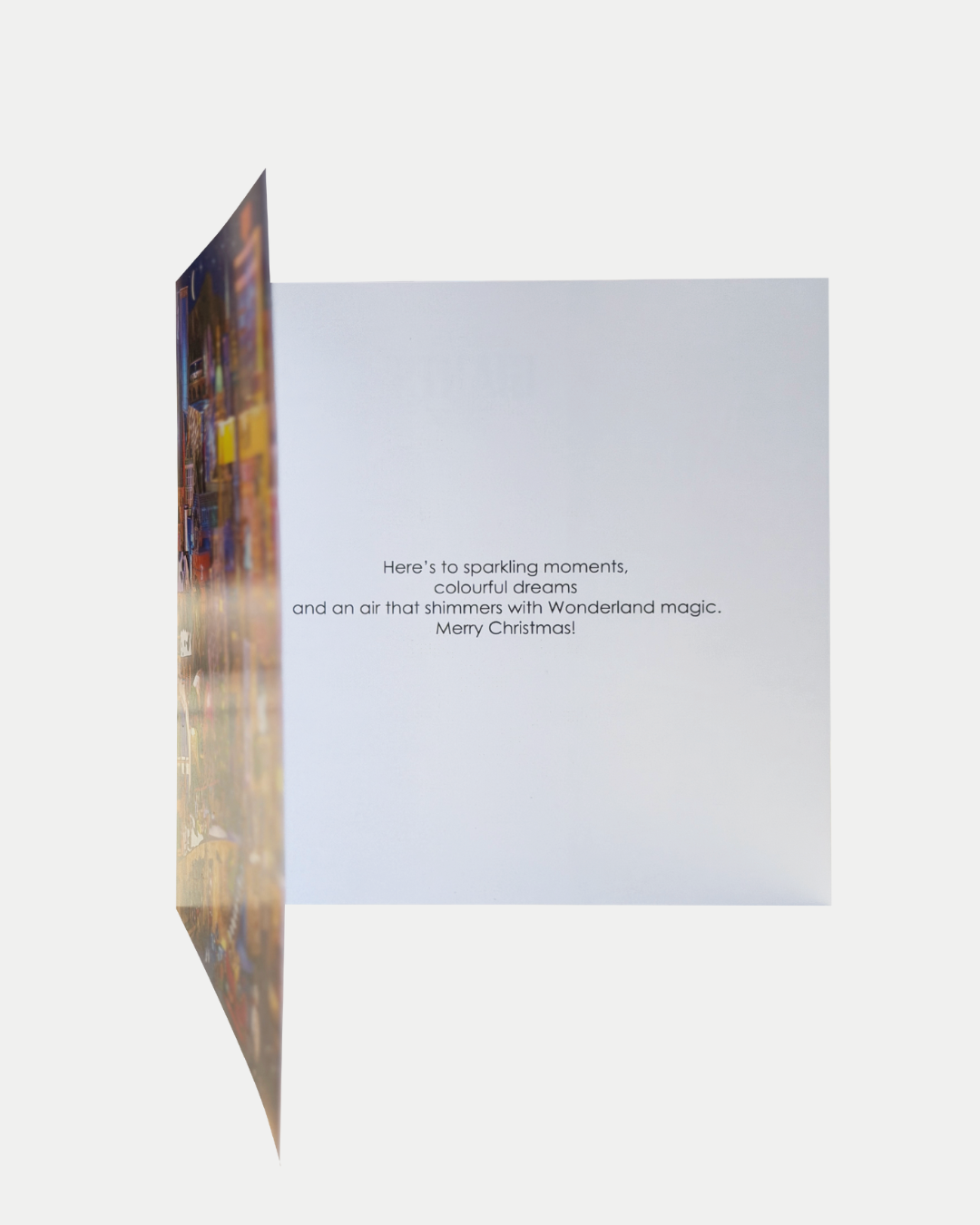 Greeting card partially open, revealing text inside that reads: Here’s to sparkling moments, colourful dreams and Wonderland magic. Merry Christmas! Part of the Belfast Giants Charity Christmas Cards from Belfast Giants Store by National Merchandise on a white background.