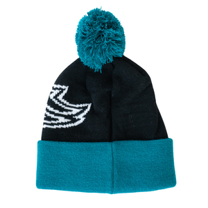 The Belfast Giants 25-26 Beanie Arched Logo by Belfast Giants Store features a black knit, teal fold-over cuff, teal pom-pom, and a white arched logo graphic on one side, perfect for fans seeking stylish team merchandise.