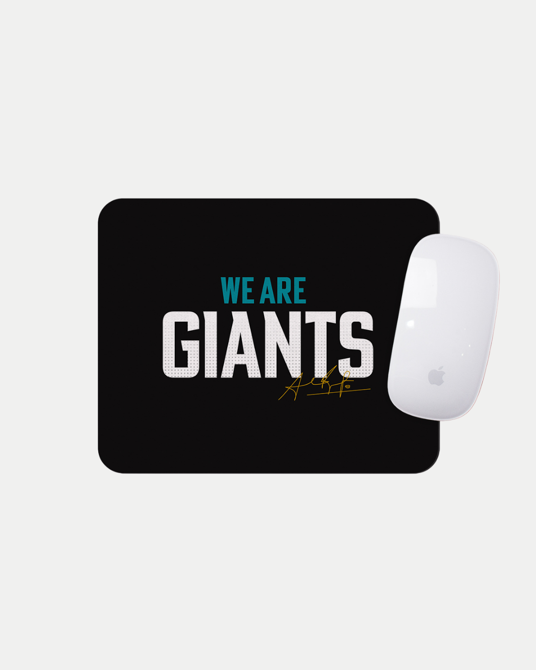 The We Are Giants Black Mousemat by Belfast Giants features bold white and blue "WE ARE GIANTS" text with a gold signature below. Made to order, it displays an Apple Magic Mouse on the top right corner of the mat.