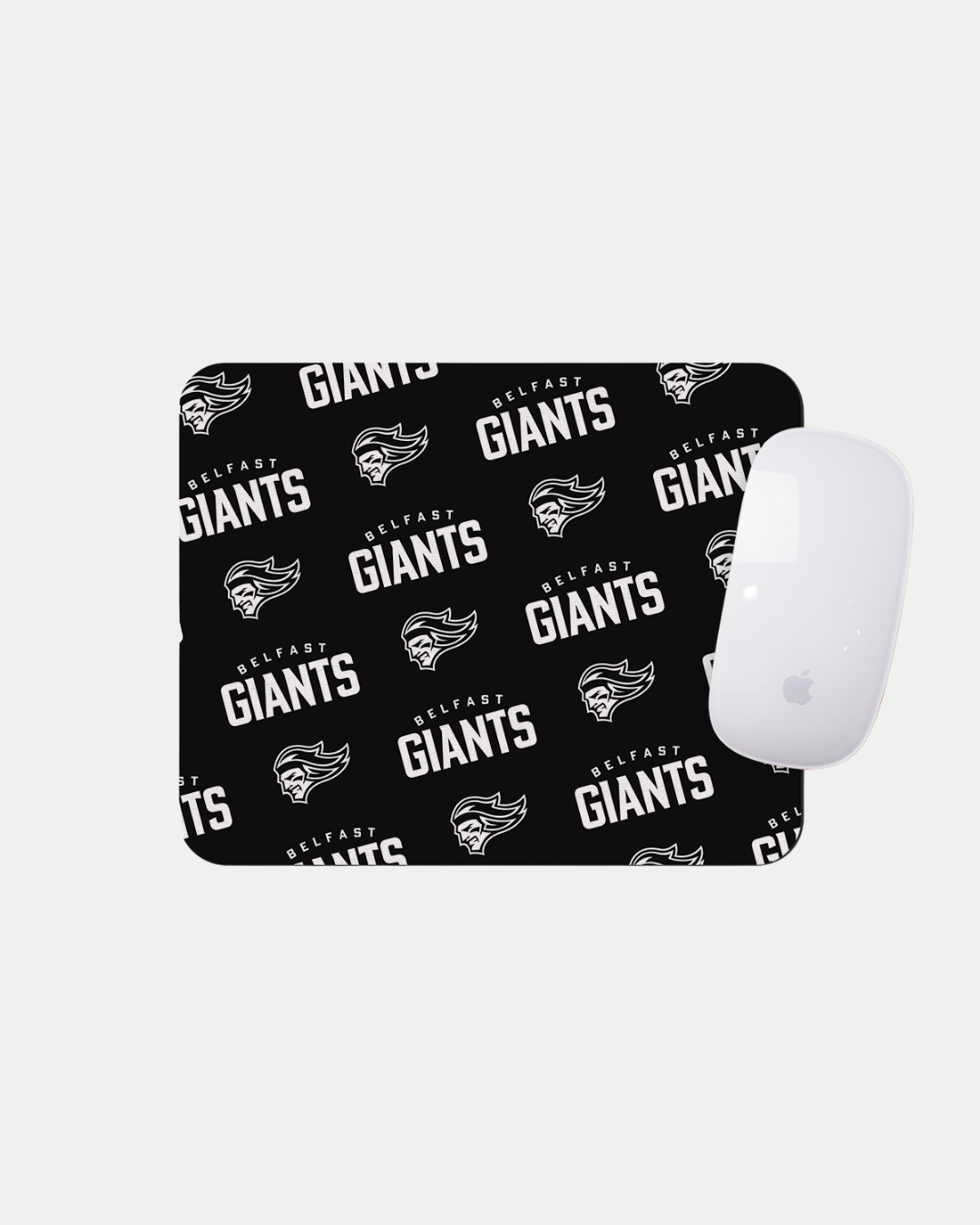 The Belfast Giants Multiple Logo Black Mousemat features a repeating white Belfast Giants text and logo pattern on black, shown with a white Apple Magic Mouse. Made to order for quality and reduced waste. Brand: Belfast Giants.