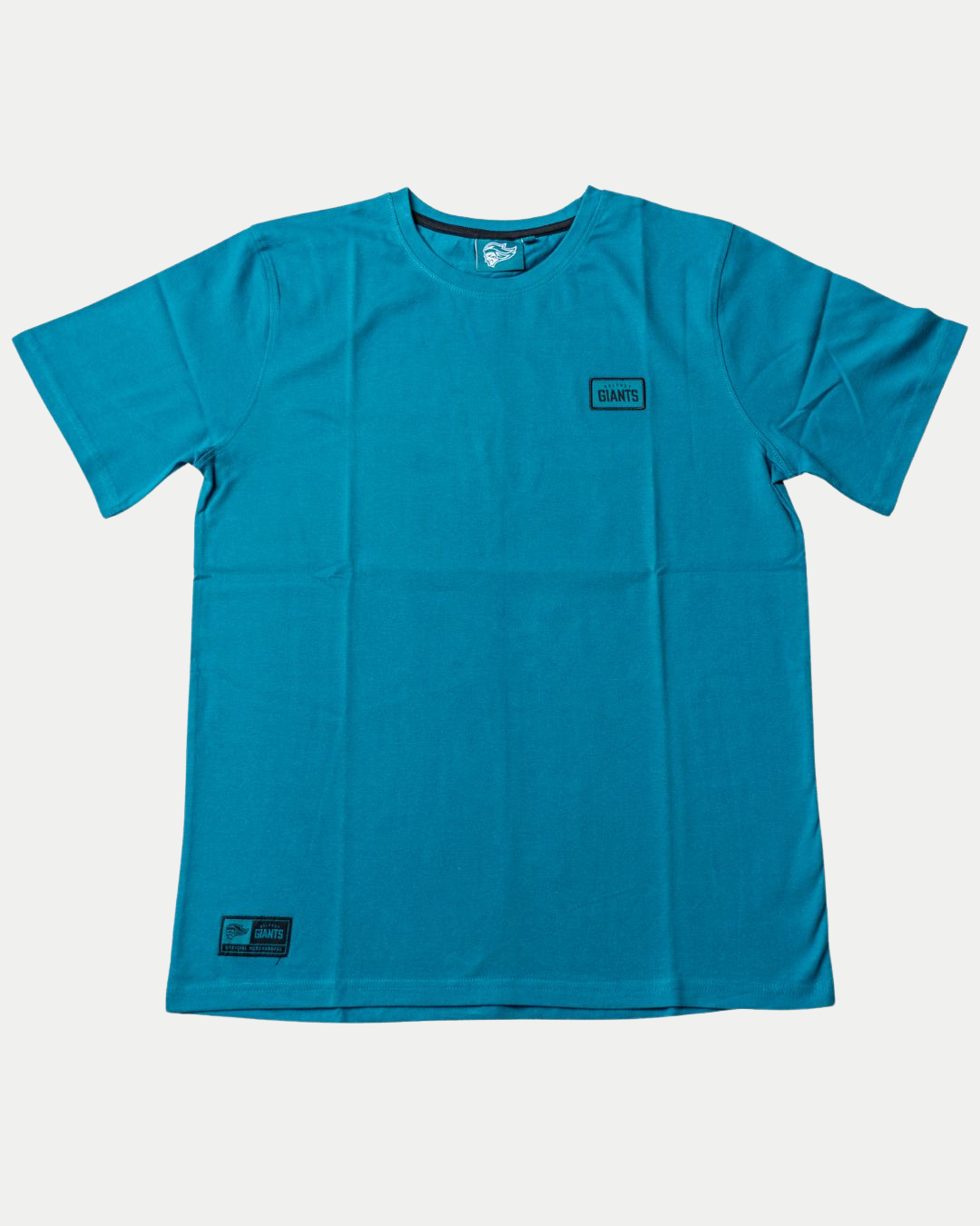 The Belfast Giants Teal T-Shirt Black Badge features short sleeves, a small rectangular Giants patch on the left chest, and another near the bottom hem, shown against a white background.