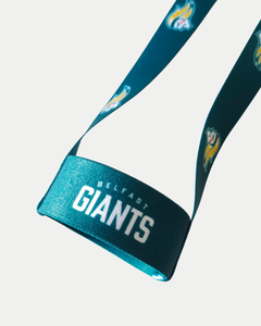A close-up of the Belfast Giants Beer Lanyard by Belfast Giants, showing "BELFAST GIANTS" in white text and a fiery logo on teal fabric. The crisp white background highlights its vibrant design.