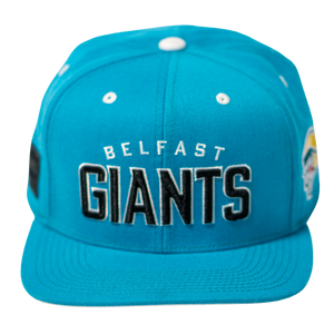 The Belfast Giants Teal Snapback Cap features GIANTS embroidered in bold black and white on the front, small white eyelets, and a colorful team crest side patch. Branded by Belfast Giants.