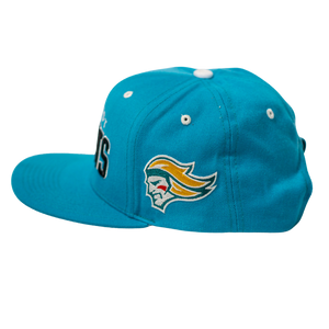 The Belfast Giants Teal Snapback Cap by Belfast Giants features an embroidered team crest with a stylized yellow-haired head on the side, a flat brim, and multiple white eyelets on top.