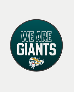 The We Are Giants Logo Puck 25-26 from Belfast Giants Store features a circular dark teal design with "WE ARE GIANTS" in bold white letters above a mascot logo, showcasing yellow and green hair accents.