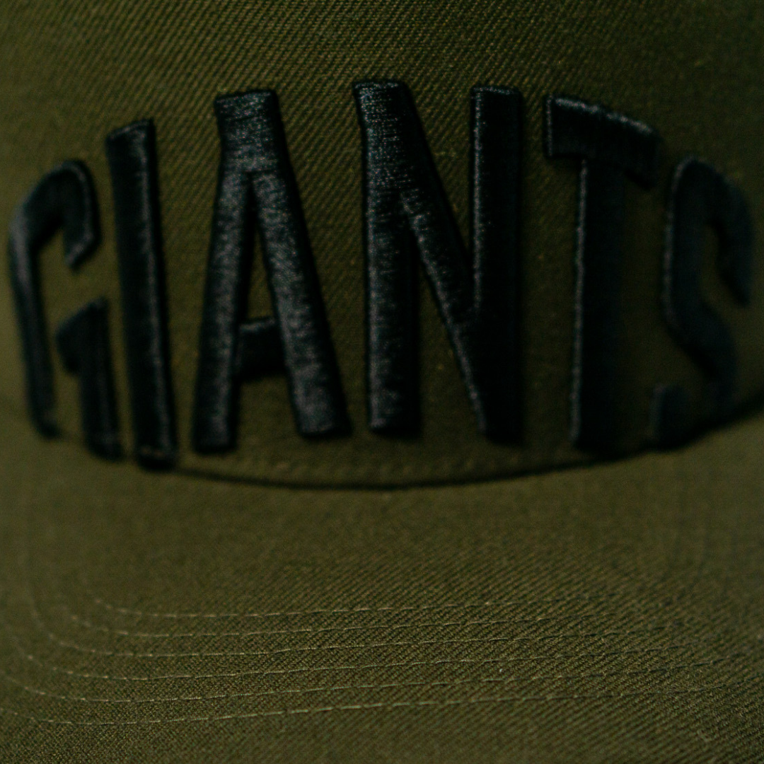 Close-up of the Belfast Giants Cap Olive by Belfast Giants, featuring GIANTS embroidered in bold black letters on the front—ideal for game day fans.