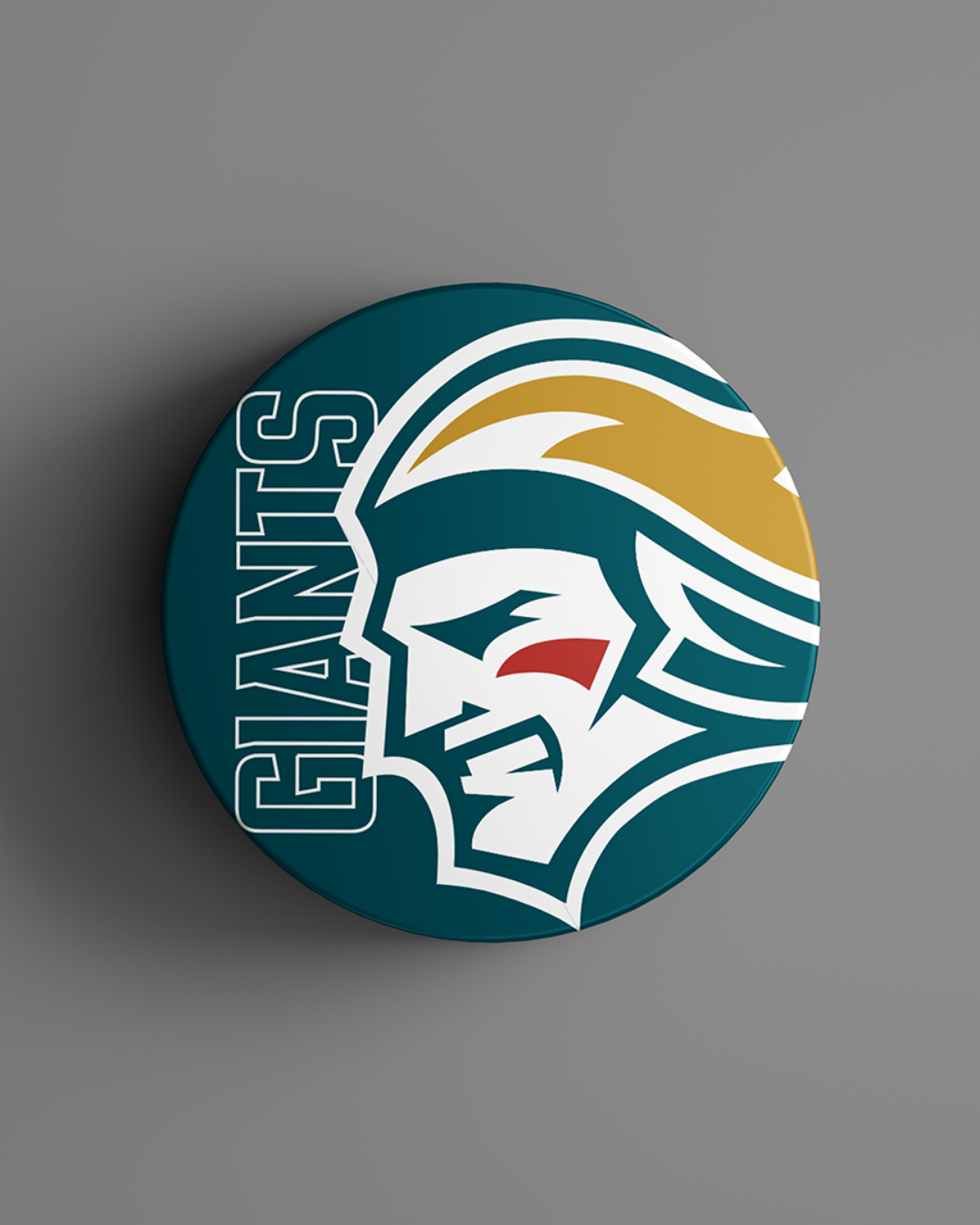The Belfast Giants Logo Puck 25-26 from the Belfast Giants Store displays a helmeted warrior in white, gold, and teal with "GIANTS" in bold teal on gray.