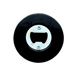 The Belfast Giants Puck Bottle Opener from the Belfast Giants Store by National Merchandise is a round black puck with a metal bottle opener in the center, attached with two screws, set against a white background.