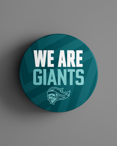 The We Are Giants Teal Logo Puck 25-26 from Belfast Giants Store by National Merchandise features bold white and light blue text above a mascot head on a striped background.