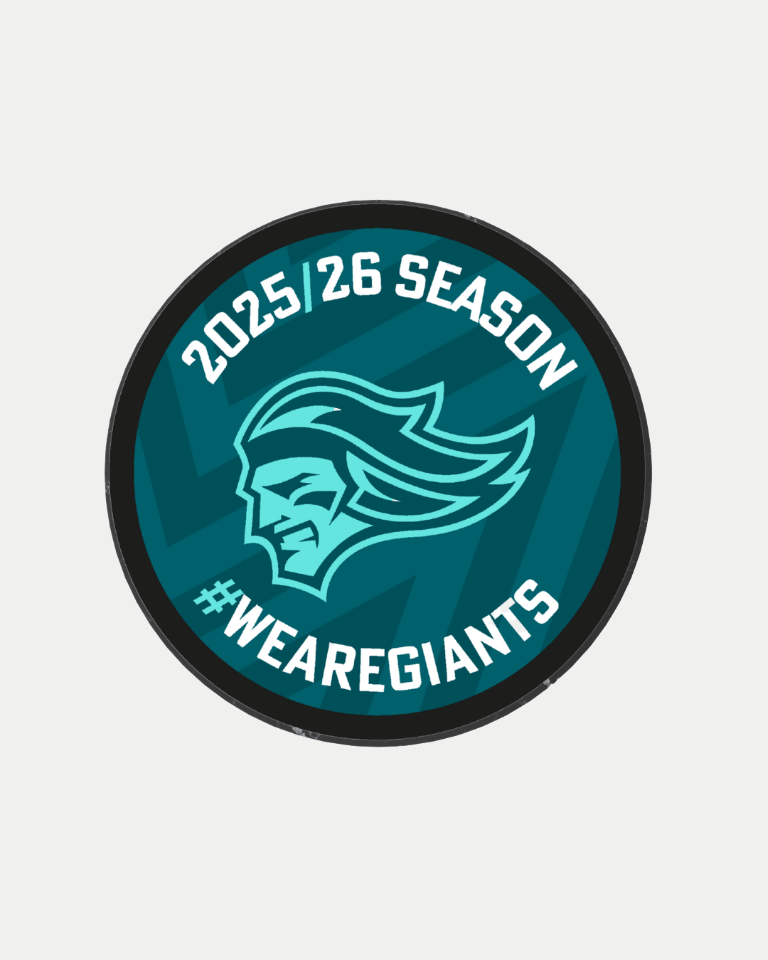 The Belfast Giants Store’s "Logo Season Puck Teal 25-26" features a stylized face logo in teal and black, surrounded by the text “2025/26 Season” and “#WEAREGIANTS.”.