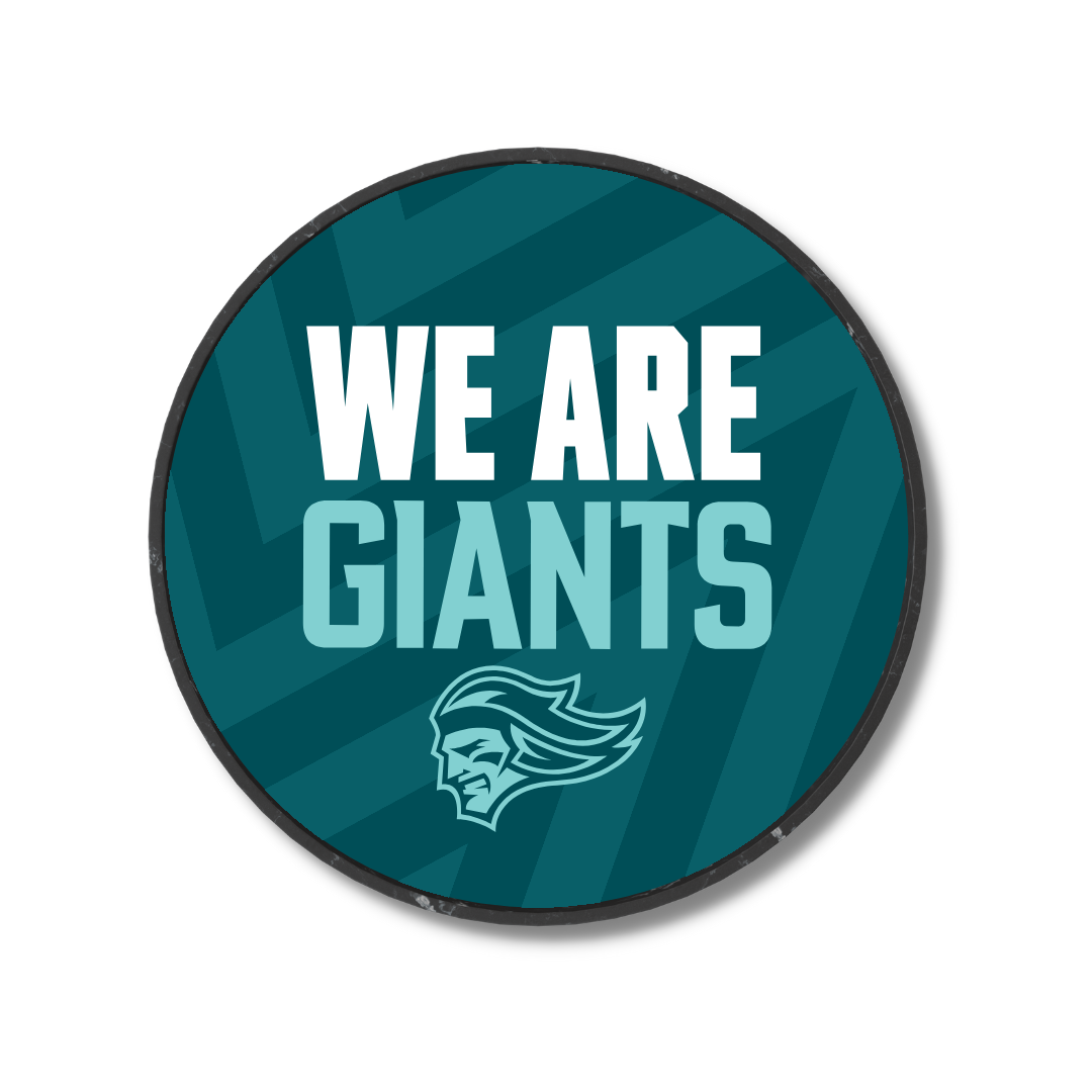 The We Are Giants Teal Logo Puck 25-26 from Belfast Giants Store features a dark teal zigzag background, white and light teal WE ARE GIANTS text, and a stylized giant head logo at the bottom.