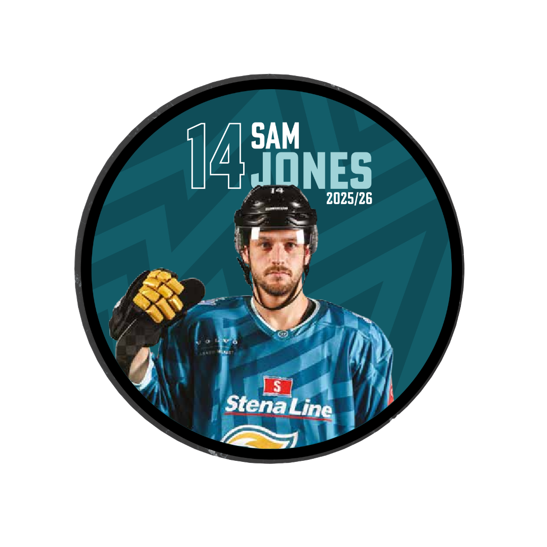A male ice hockey player in blue gear and helmet stands holding his stick. The circular 2025-26 Player Puck features Belfast Giants branding, number 14 Sam Jones, Stena Line on the jersey, and is a striking limited edition tribute.
