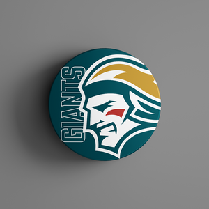 The Belfast Giants Logo Puck 25-26 features a round pin with a stylized warrior profile in white, yellow, red, and teal beside bold teal “GIANTS” lettering on a matching background. Available from Belfast Giants Store by National Merchandise.
