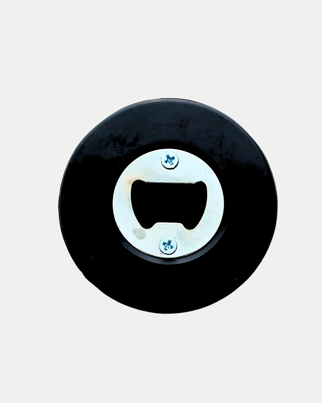 The Belfast Giants Puck Bottle Opener by Belfast Giants Store features a round black puck with a metal bottle opener in the center, secured by two screws, displayed against a plain white background.