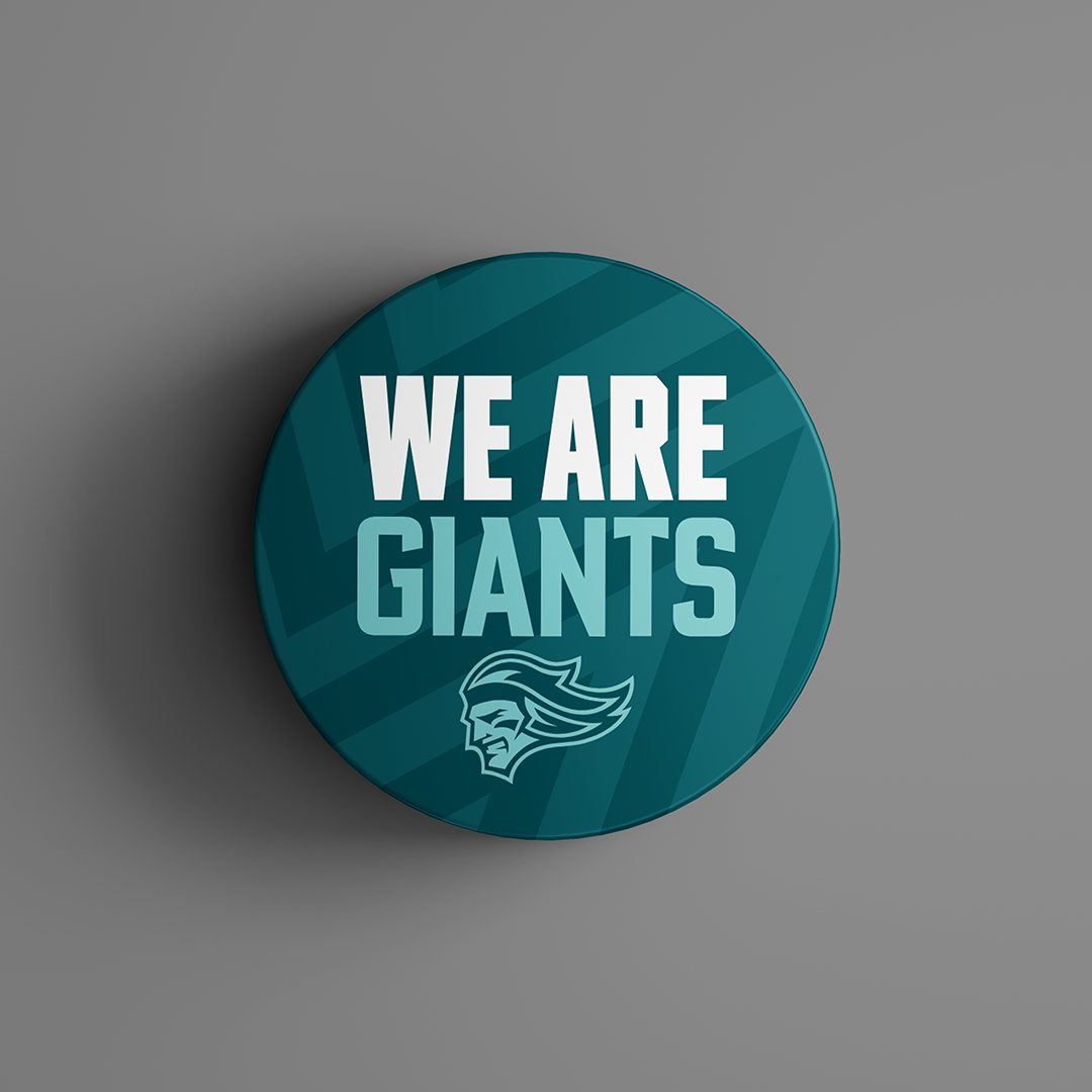 The We Are Giants Teal Logo Puck 25-26 from Belfast Giants Store by National Merchandise features bold white and light blue text over a stylized giants head on a teal, geometric background.