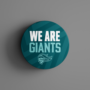 The We Are Giants Teal Logo Puck 25-26 from Belfast Giants Store by National Merchandise features bold white and light blue text over a stylized giants head on a teal, geometric background.